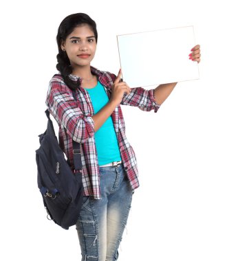Sırt çantalı genç Hintli kadın beyaz bir zeminde duran ve beyaz tahta tutan,.