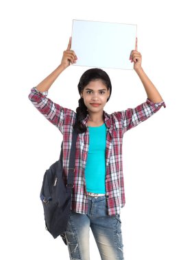 Sırt çantalı genç Hintli kadın beyaz bir zeminde duran ve beyaz tahta tutan,.