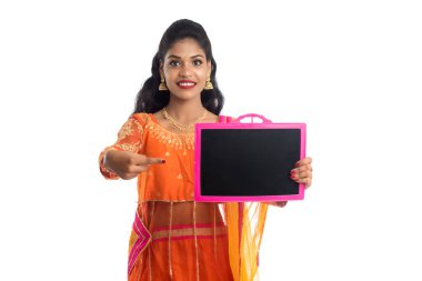 Elinde beyaz bir arka planda boş bir tahtayla poz veren güzel bir genç kadın.