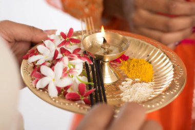 Güzel Hintli genç kız elinde pooja thali tutarken ya da beyaz bir arka planda ibadet ederken
