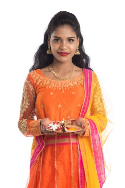 Güzel Hintli genç kız elinde pooja thali tutarken ya da beyaz bir arka planda ibadet ederken