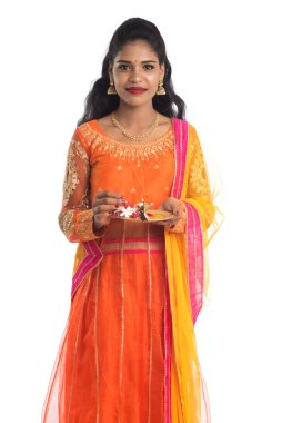 Güzel Hintli genç kız elinde pooja thali tutarken ya da beyaz bir arka planda ibadet ederken