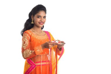 Güzel Hintli genç kız elinde pooja thali tutarken ya da beyaz bir arka planda ibadet ederken