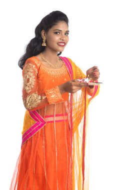 Güzel Hintli genç kız elinde pooja thali tutarken ya da beyaz bir arka planda ibadet ederken