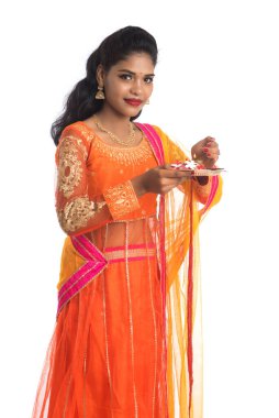 Güzel Hintli genç kız elinde pooja thali tutarken ya da beyaz bir arka planda ibadet ederken