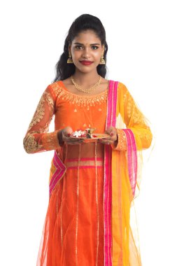 Güzel Hintli genç kız elinde pooja thali tutarken ya da beyaz bir arka planda ibadet ederken