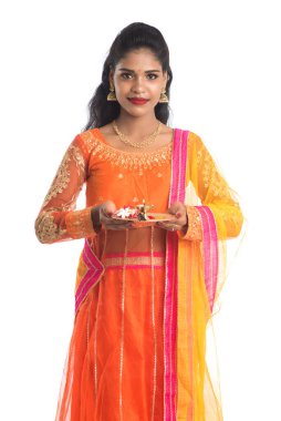 Güzel Hintli genç kız elinde pooja thali tutarken ya da beyaz bir arka planda ibadet ederken