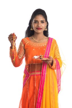 Raksha Bandhan vesilesiyle Rakhi 'ye Pooja thali' yi gösteren güzel Hintli kız. Kız kardeş Rakhi 'yi erkek kardeşine olan yoğun sevgisinin sembolü olarak bağlıyor..