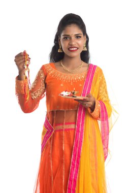 Raksha Bandhan vesilesiyle Rakhi 'ye Pooja thali' yi gösteren güzel Hintli kız. Kız kardeş Rakhi 'yi erkek kardeşine olan yoğun sevgisinin sembolü olarak bağlıyor..