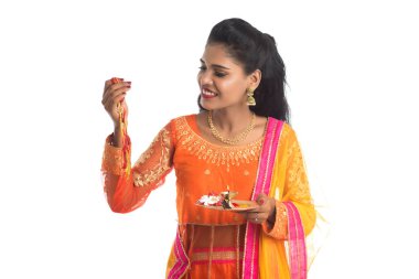 Raksha Bandhan vesilesiyle Rakhi 'ye Pooja thali' yi gösteren güzel Hintli kız. Kız kardeş Rakhi 'yi erkek kardeşine olan yoğun sevgisinin sembolü olarak bağlıyor..