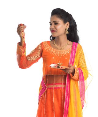 Raksha Bandhan vesilesiyle Rakhi 'ye Pooja thali' yi gösteren güzel Hintli kız. Kız kardeş Rakhi 'yi erkek kardeşine olan yoğun sevgisinin sembolü olarak bağlıyor..