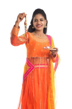 Raksha Bandhan vesilesiyle Rakhi 'ye Pooja thali' yi gösteren güzel Hintli kız. Kız kardeş Rakhi 'yi erkek kardeşine olan yoğun sevgisinin sembolü olarak bağlıyor..
