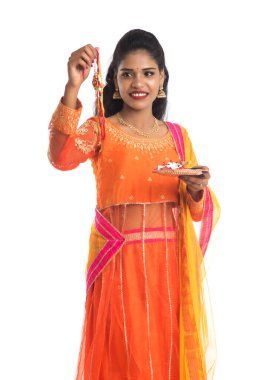 Raksha Bandhan vesilesiyle Rakhi 'ye Pooja thali' yi gösteren güzel Hintli kız. Kız kardeş Rakhi 'yi erkek kardeşine olan yoğun sevgisinin sembolü olarak bağlıyor..