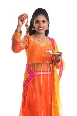 Raksha Bandhan vesilesiyle Rakhi 'ye Pooja thali' yi gösteren güzel Hintli kız. Kız kardeş Rakhi 'yi erkek kardeşine olan yoğun sevgisinin sembolü olarak bağlıyor..