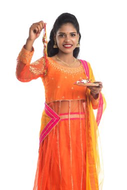 Raksha Bandhan vesilesiyle Rakhi 'ye Pooja thali' yi gösteren güzel Hintli kız. Kız kardeş Rakhi 'yi erkek kardeşine olan yoğun sevgisinin sembolü olarak bağlıyor..