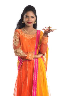 Güzel Hintli genç kız elinde pooja thali tutarken ya da beyaz bir arka planda ibadet ederken