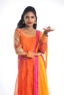 Güzel Hintli genç kız elinde pooja thali tutarken ya da beyaz bir arka planda ibadet ederken