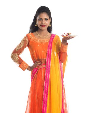 Güzel Hintli genç kız elinde pooja thali tutarken ya da beyaz bir arka planda ibadet ederken