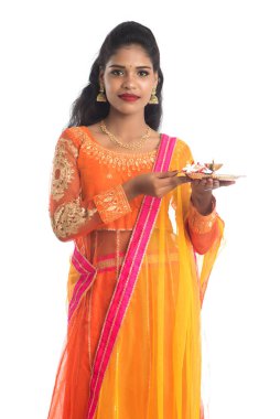 Güzel Hintli genç kız elinde pooja thali tutarken ya da beyaz bir arka planda ibadet ederken