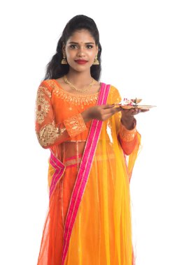 Güzel Hintli genç kız elinde pooja thali tutarken ya da beyaz bir arka planda ibadet ederken