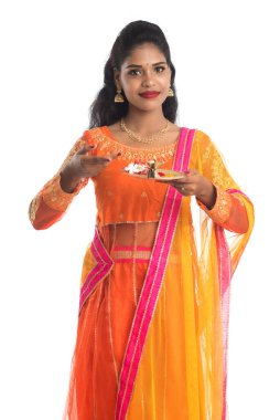 Güzel Hintli genç kız elinde pooja thali tutarken ya da beyaz bir arka planda ibadet ederken