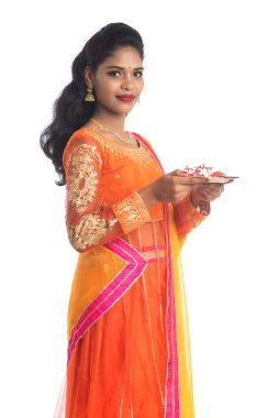 Güzel Hintli genç kız elinde pooja thali tutarken ya da beyaz bir arka planda ibadet ederken