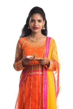 Güzel Hintli genç kız elinde pooja thali tutarken ya da beyaz bir arka planda ibadet ederken