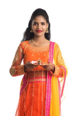 Güzel Hintli genç kız elinde pooja thali tutarken ya da beyaz bir arka planda ibadet ederken