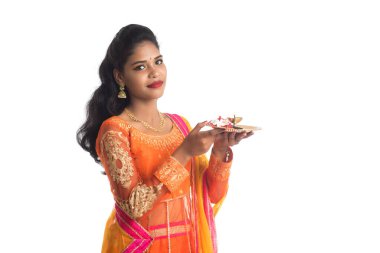 Güzel Hintli genç kız elinde pooja thali tutarken ya da beyaz bir arka planda ibadet ederken