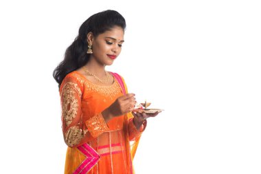 Güzel Hintli genç kız elinde pooja thali tutarken ya da beyaz bir arka planda ibadet ederken