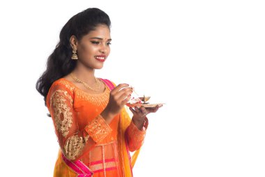 Güzel Hintli genç kız elinde pooja thali tutarken ya da beyaz bir arka planda ibadet ederken