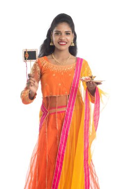 Raksha Bandhan vesilesiyle Rakhi 'ye pooja thali ve kara tahtayla güzel bir Hintli kız gösteriyordu. Kız kardeş Rakhi 'yi erkek kardeşine olan yoğun sevgisinin sembolü olarak bağlıyor..