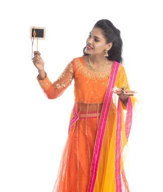 Raksha Bandhan vesilesiyle Rakhi 'ye pooja thali ve kara tahtayla güzel bir Hintli kız gösteriyordu. Kız kardeş Rakhi 'yi erkek kardeşine olan yoğun sevgisinin sembolü olarak bağlıyor..