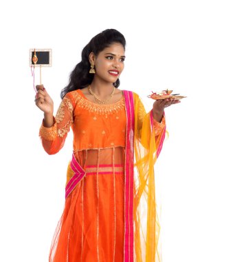 Raksha Bandhan vesilesiyle Rakhi 'ye pooja thali ve kara tahtayla güzel bir Hintli kız gösteriyordu. Kız kardeş Rakhi 'yi erkek kardeşine olan yoğun sevgisinin sembolü olarak bağlıyor..