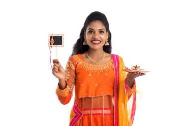 Raksha Bandhan vesilesiyle Rakhi 'ye pooja thali ve kara tahtayla güzel bir Hintli kız gösteriyordu. Kız kardeş Rakhi 'yi erkek kardeşine olan yoğun sevgisinin sembolü olarak bağlıyor..