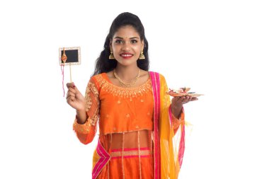 Raksha Bandhan vesilesiyle Rakhi 'ye pooja thali ve kara tahtayla güzel bir Hintli kız gösteriyordu. Kız kardeş Rakhi 'yi erkek kardeşine olan yoğun sevgisinin sembolü olarak bağlıyor..