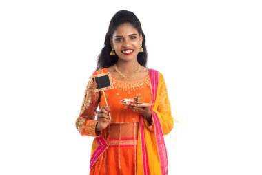 Raksha Bandhan vesilesiyle Rakhi 'ye pooja thali ve kara tahtayla güzel bir Hintli kız gösteriyordu. Kız kardeş Rakhi 'yi erkek kardeşine olan yoğun sevgisinin sembolü olarak bağlıyor..