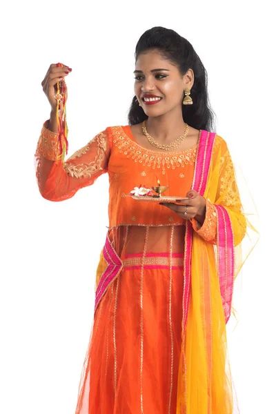 Raksha Bandhan vesilesiyle Rakhi 'ye Pooja thali' yi gösteren güzel Hintli kız. Kız kardeş Rakhi 'yi erkek kardeşine olan yoğun sevgisinin sembolü olarak bağlıyor..