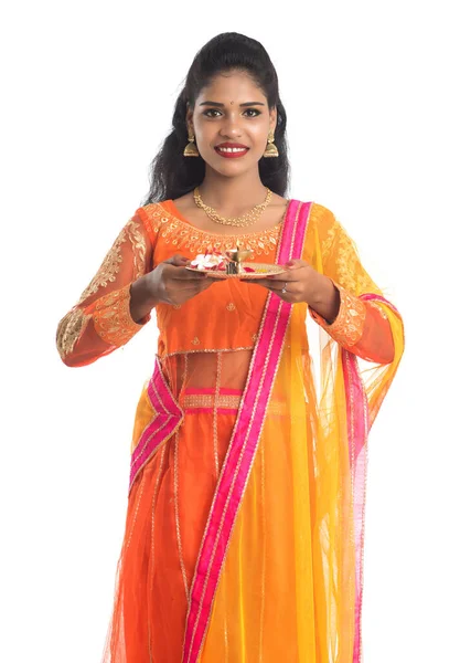 Güzel Hintli genç kız elinde pooja thali tutarken ya da beyaz bir arka planda ibadet ederken