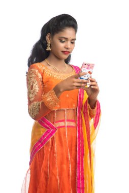 Genç Hintli geleneksel kız beyaz arka planda izole edilmiş cep telefonu ya da akıllı telefon kullanıyor.