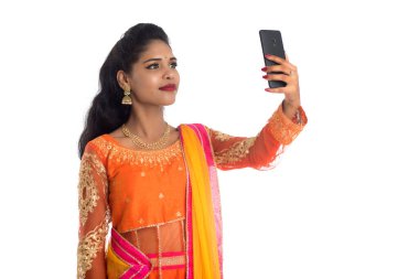 Genç Hintli geleneksel kız beyaz arka planda izole edilmiş cep telefonu ya da akıllı telefon kullanıyor.