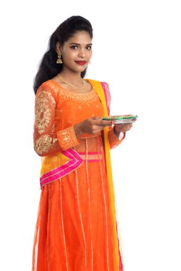 Beyaz arka planda ışık festivali sırasında Diya 'yı, Diwali' yi veya Deepavali 'yi kutlayan kızı tutan Hintli Geleneksel Kız Portresi