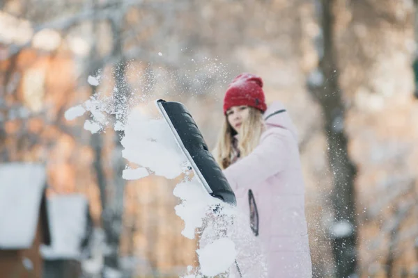 Молода дівчина-підліток прибирає сніг біля будинку, тримаючи лопату і весло проводити час — стокове фото