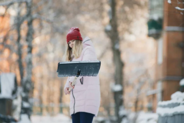 若い十代の少女をきれいに家の近くの雪シャベルとパドルを過ごす時間を保持 — ストック写真