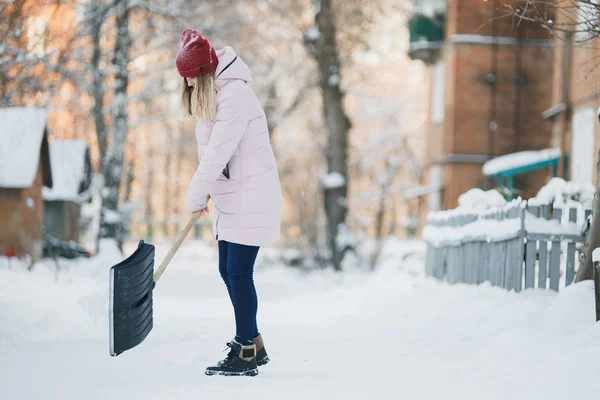 若い十代の少女をきれいに家の近くの雪シャベルとパドルを過ごす時間を保持 — ストック写真