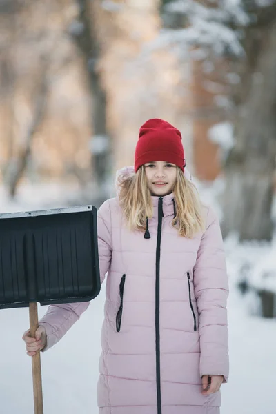 若い十代の少女をきれいに家の近くの雪シャベルとパドルを過ごす時間を保持 — ストック写真