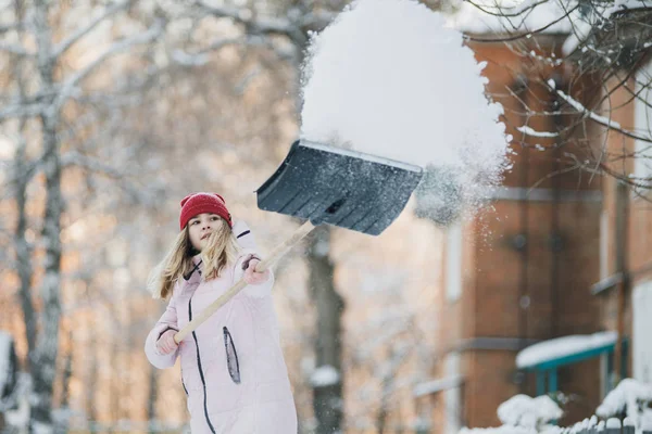 Tenåringsjente vasker snø ved huset, holder spade og padler, tilbringer tid – stockfoto