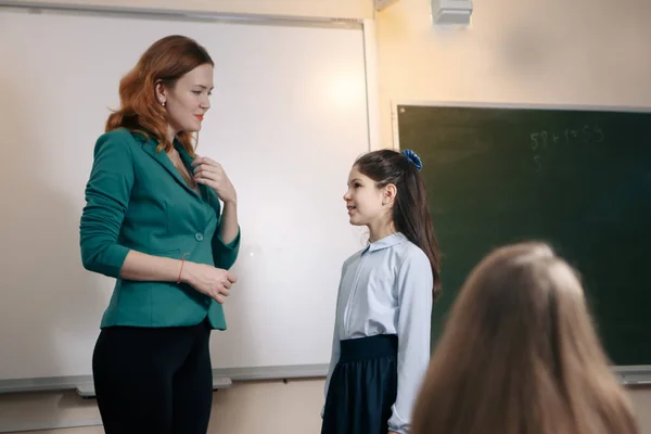 Sonriente profesor de edad avanzada cerca de la pizarra preguntando a los estudiantes en la lección de matemáticas — Foto de Stock