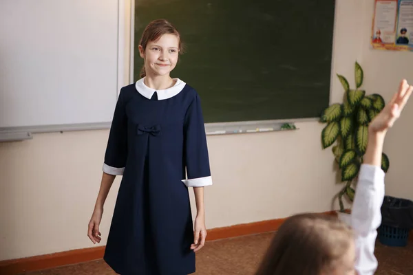 Schoolgirl posing in front of a blackboard — Stock Photo, Image