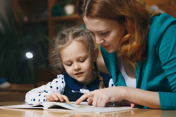 放課後の子供を助けることの母。幼児家庭教師の助けを借りての宿題します。ホーム教育コンセプト. — ストック写真